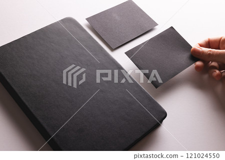 Black notebook and caucasian woman holding black paper card on white background Black notebook and caucasian woman holding black paper card on white background 121024550
