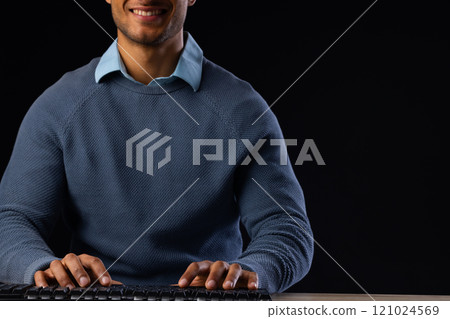 Biracial businessman using computer with copy space on black background Biracial businessman using computer with copy space on black background 121024569