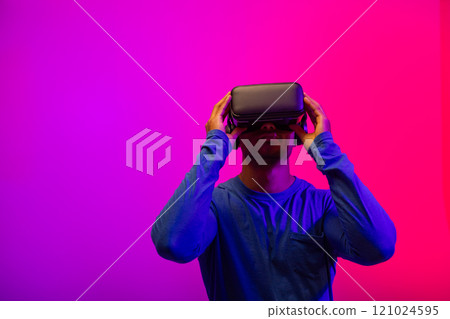 Biracial businessman using vr headset on neon pink to purple background Biracial businessman using vr headset on neon pink to purple background 121024595