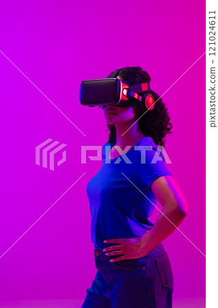 Vertical image of biracial woman with vr headset on neon pink to purple background Vertical image of biracial woman with vr headset on neon pink to purple background 121024611