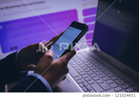 Biracial businesswoman using smartphone and laptop on black background 121024651