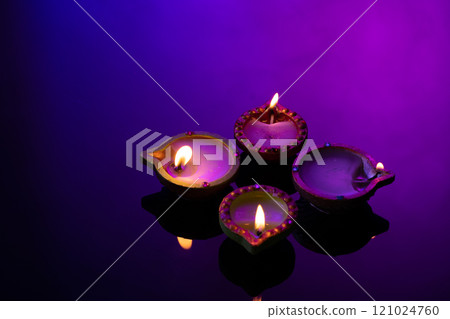 Close up of four diwali candles with copy space on purple background Close up of four diwali candles with copy space on purple background 121024760