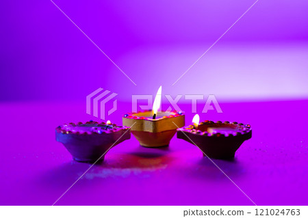 Close up of three diwali candles with copy space on purple background Close up of three diwali candles with copy space on purple background 121024763