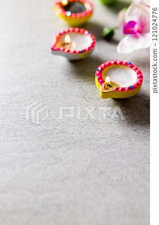 Close up of three diwali candles and flowers with copy space on grey background 121024776