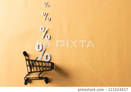 Shopping trolley and white percent signs with copy space on yellow background Shopping trolley and white percent signs with copy space on yellow background 121024837