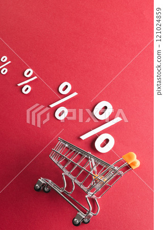 Shopping trolley and white percent signs with copy space on red background 121024859