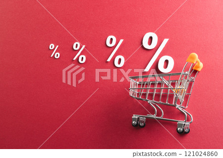 Shopping trolley and white percent signs with copy space on red background Shopping trolley and white percent signs with copy space on red background 121024860