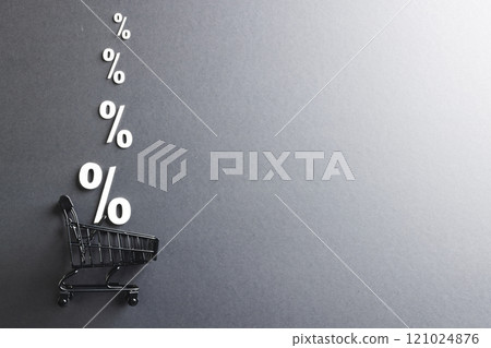 Shopping trolley and white percent signs with copy space on grey background 121024876