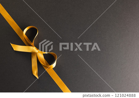 Gold gift ribbon and bow with copy space on black background 121024888