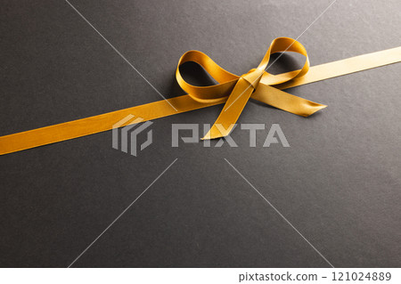 Gold gift ribbon and bow with copy space on black background Gold gift ribbon and bow with copy space on black background 121024889