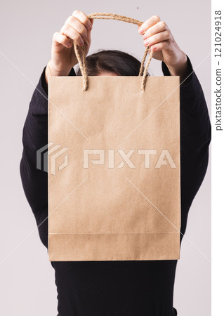 Caucasian woman holding paper shopping bag with copy space on white background 121024918