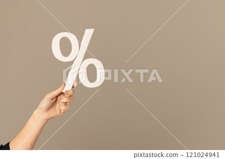 Video of hand of caucasian woman holding white percent sign with copy space against grey background 121024941