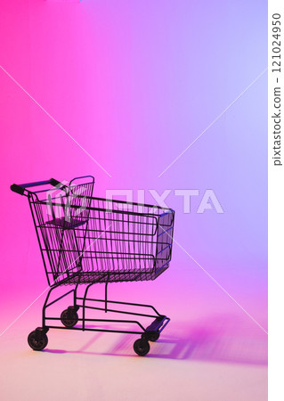 Vertical image of shopping trolley with copy space over neon purple background 121024950