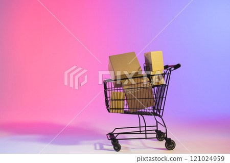 Shopping trolley with boxes and copy space over neon purple background 121024959