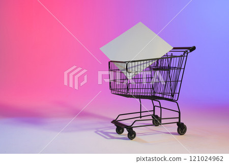 Shopping trolley with blank canvas and copy space over neon purple background 121024962
