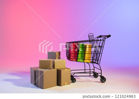 Shopping trolley with bags, boxes and copy space over neon purple background Shopping trolley with bags, boxes and copy space over neon purple background 121024963