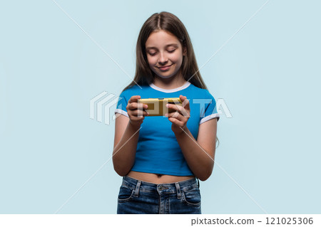 Girl holding smartphone, engaged and focused, possibly gaming or browsing. 121025306