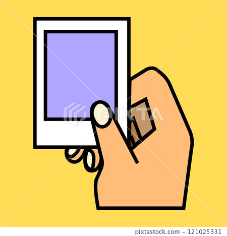 A hand holding a blank polaroid frame against a bright yellow background surrounded by creativity 121025331