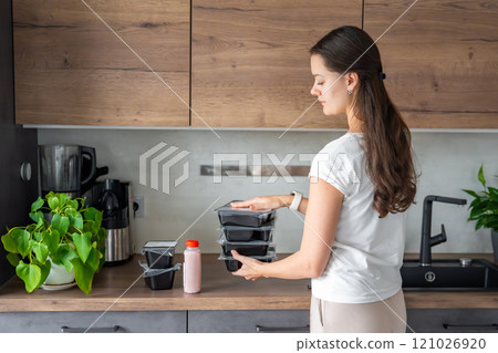 Young woman with healthy diet plan for weight loss, delivery of daily ready meal menu. Food ordered with mobile phone app. Balanced portion with dish. Pre-cooking. Young woman with healthy diet plan for weight loss, delivery of daily ready meal menu. Food ordered with mobile phone app. Balanced portion with dish. Pre-cooking. 121026920
