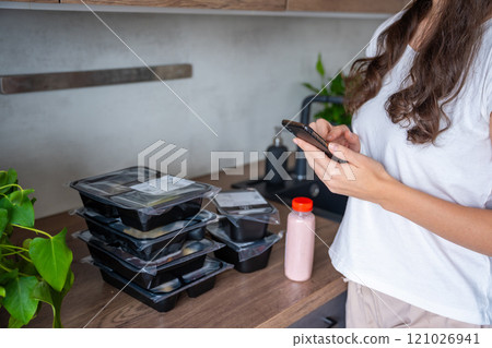 Black boxes with healthy diet plan for weight loss, delivery of daily ready meal menu. Food ordered with mobile phone app. Balanced portion with dish. Pre-cooking. 121026941