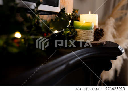 Christmas time, Festive candles glowing on mantel with holly and pinecone decoration, at home Christmas time, Festive candles glowing on mantel with holly and pinecone decoration, at home 121027023