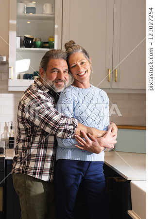 Embracing in cozy kitchen, mature couple sharing warm holiday moments together, at home 121027254