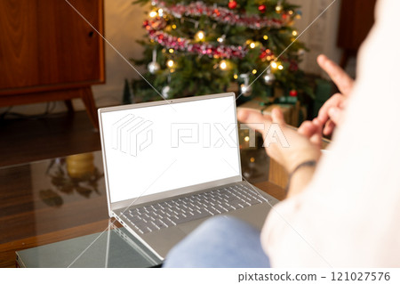senior man video chatting on laptop at home near Christmas tree, copy space 121027576