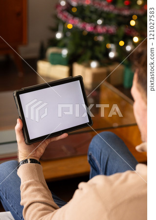senior man using tablet at home near Christmas tree, enjoying holiday season, copy space senior man using tablet at home near Christmas tree, enjoying holiday season, copy space 121027583