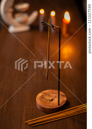 incense stick smokes on a wooden stand on a dark background. Aromatherapy, Smoke while burning incense. smoke for prayers and meditation. prayer to buddha. incense for relaxation and yoga 121027599