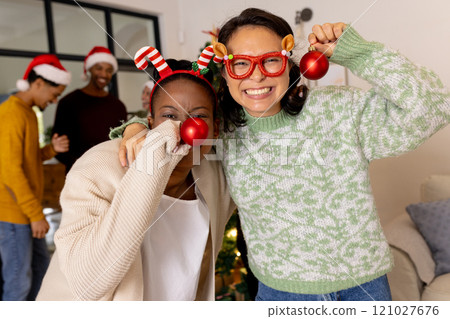 Celebrating Christmas at home, multiracial friends wearing festive accessories and smiling together 121027676
