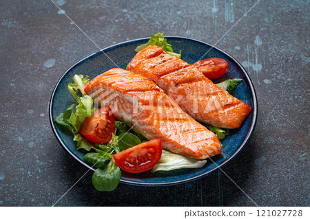 Grilled fish salmon steak with vegetables salad on ceramic plate on rustic stone background angle view, balanced diet, healthy nutrition salad meal with salmon and veggies 121027728