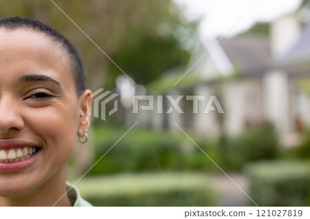 Smiling young woman enjoying outdoor time in lush garden setting, copy space 121027819