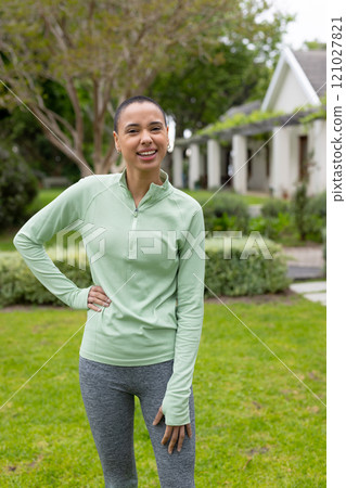 Smiling woman in activewear enjoying outdoor exercise in lush garden 121027821