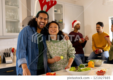 Multiracial friends celebrating christmas in kitchen, preparing salad at home Multiracial friends celebrating christmas in kitchen, preparing salad at home 121027885