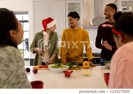 Christmas time, preparing festive meal in kitchen, multiracial friends laughing at home Christmas time, preparing festive meal in kitchen, multiracial friends laughing at home 121027895