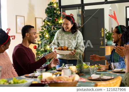 Sharing laughter, multiracial friends at festive christmas dinner, at home 121027906