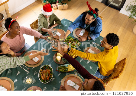 Young multiracial friends celebrating christmas dinner, toasting at home Young multiracial friends celebrating christmas dinner, toasting at home 121027930