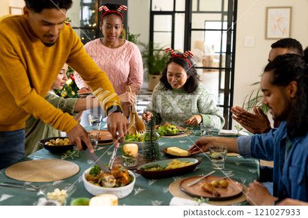 Christmas time, young multiracial friends enjoying festive holiday meal together, at home 121027933