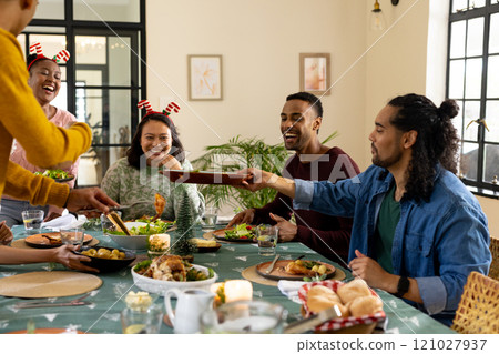 Christmas time, young multiracial friends enjoying festive holiday meal together, at home Christmas time, young multiracial friends enjoying festive holiday meal together, at home 121027937