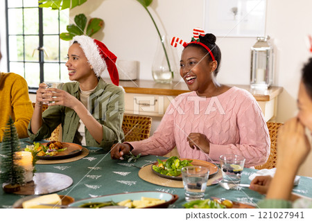 Christmas time, young multiracial friends enjoying festive meal together, at home 121027941