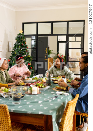 Multiracial friends laughing and having festive christmas meal together, at home 121027947