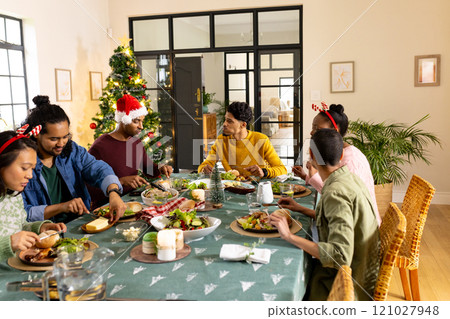 Sharing joyful moments, multiracial friends having festive Christmas meal together at home 121027948