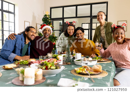 multiracial friends celebrating Christmas together, enjoying festive meal and holiday cheer, at home multiracial friends celebrating Christmas together, enjoying festive meal and holiday cheer, at home 121027950