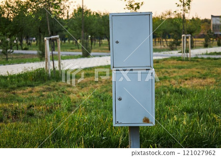 Small outdoor electrical enclosure, cabinet on pole in city park Small outdoor electrical enclosure, cabinet on pole in city park 121027962