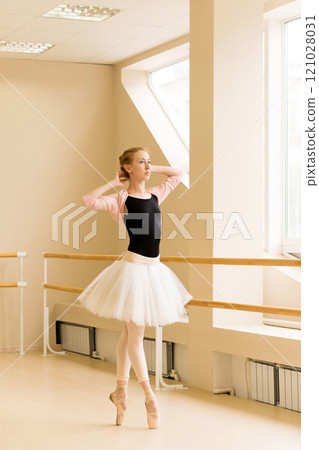 Ballerina strikes delicate pose with arms raised 121028031