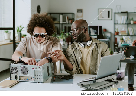 African American man pointing at small detail while his biracial coworker connecting wires 121028168