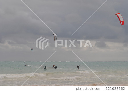 Kitesurfing man with kite in sky on kiteboard in sea riding waves with water splash. Water sports. Hobby and fun in summer time. Kiteboarding sport 121028662