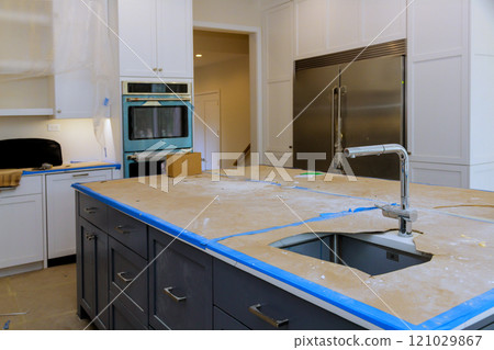 Renovation work is in progress in modern kitchen featuring exposed unfinished countertops appliances awaiting installation. 121029867