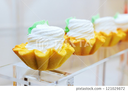 Brightly colored dessert cups are arranged in bakery case each cup, shaped like flower, is topped with fluffy whipped cream, decorative green accents. 121029872