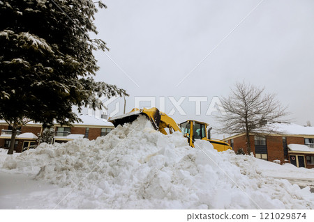 Snow plow is actively removing deep snow from residential street on winter day, surrounded by homes.. Snow plow is actively removing deep snow from residential street on winter day, surrounded by homes.. 121029874